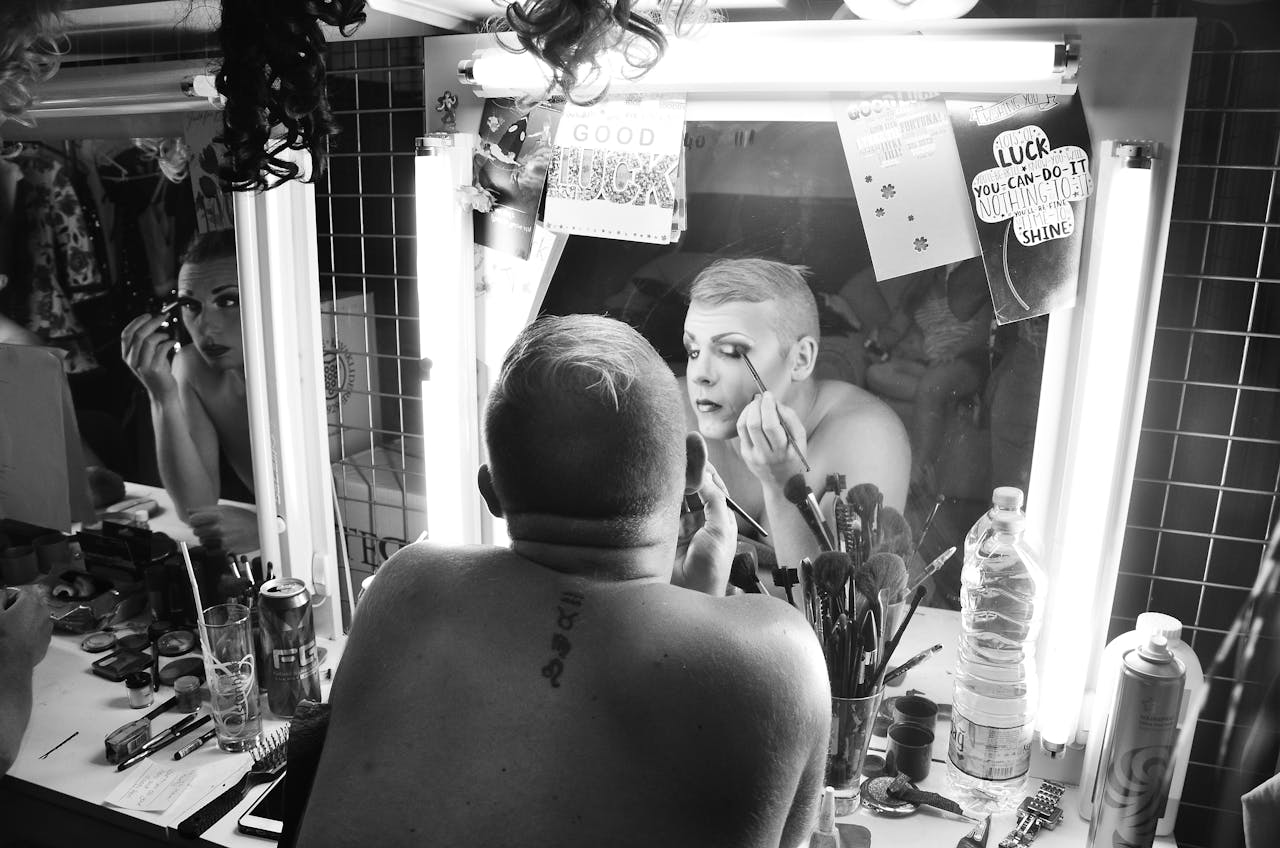 trusted-partner Drag queen applying makeup in dressing room, showcasing artistry and transformation.
