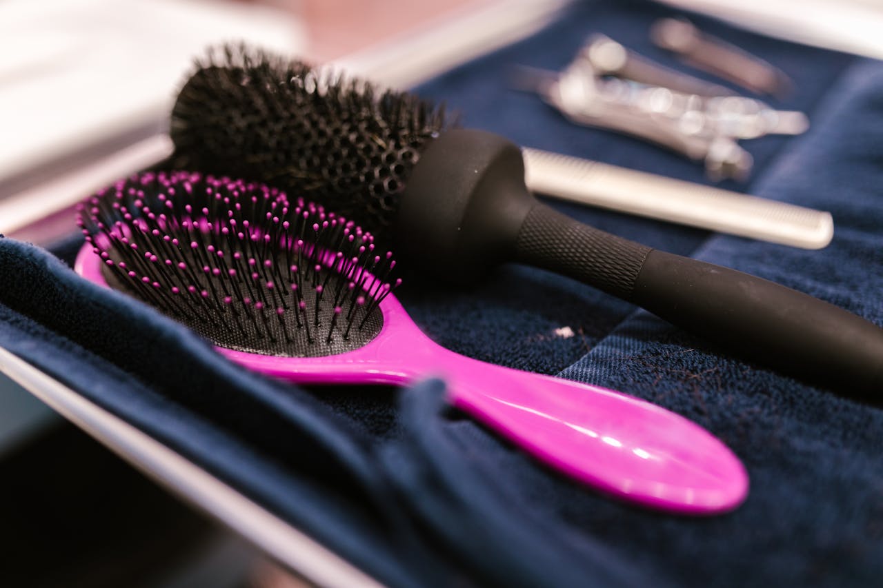 vision Close-up of pink and black hairbrushes on a towel in a salon setting.